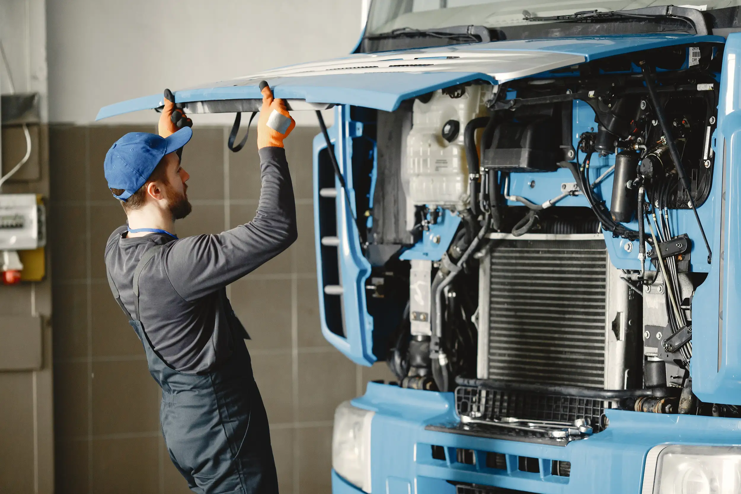 A mechanic opening up the hood of the truck for inspection.